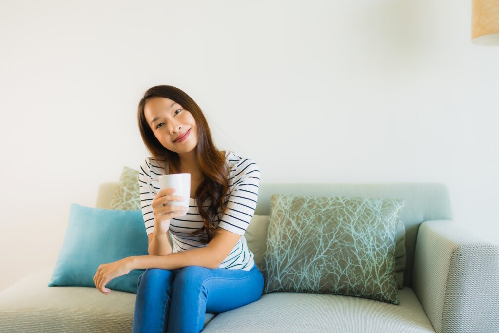Girl sitting on a comfy beanbag chair in a creatively decorated room, smiling and holding a mug of tea.