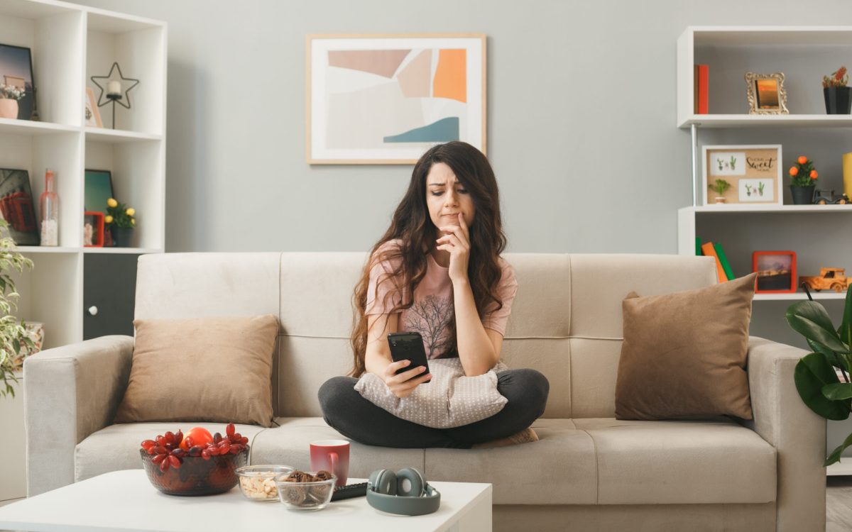 Girl sitting on a comfy beanbag chair in a creatively decorated room, smiling and holding a mug of tea.